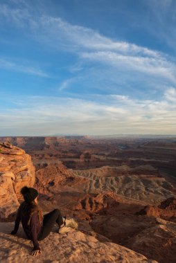 Utah 'taki Dead Horse Point Eyalet Parkı' nda genç bir kadın yürüyüşçünün huzurlu manzarası.