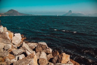 Dağların arka planında nefes kesici bir deniz ve kaya manzarası.