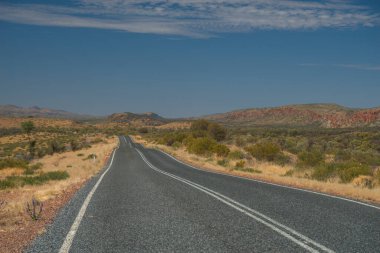 Vahşi bir manzaranın yanında bir otoyolun perspektif görüntüsü.
