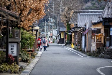 Japonya, Yufuin 'de dar bir sokakta yürüyen insanlar.
