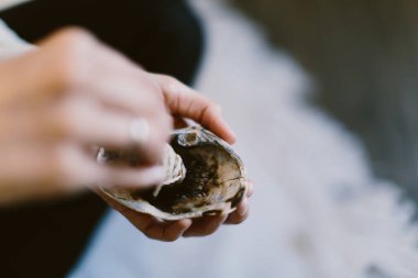 Adaçayı yakan ve deniz kabuğunun üzerinde tutan bir kadının yakın plan fotoğrafı..