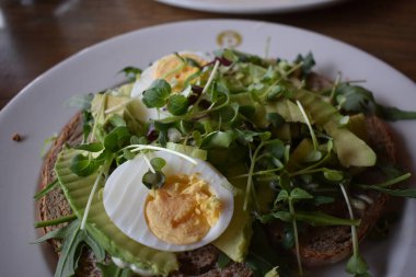 Haşlanmış yumurta, avokado ve mikroyeşil ile yakın plan bir tost.