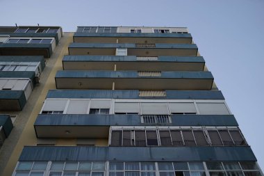 Açık mavi gökyüzüne karşı bir apartman kompleksinin alçak açılı görüntüsü