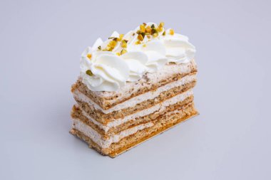 Beyaz bir arka planda krema ve fındıklı Mille-feuille pastasının yakın plan çekimi.