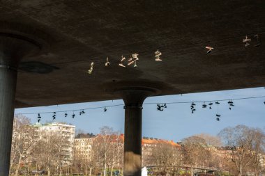 Stockholm şehir merkezindeki Ralambshovsparken köprüsünün altındaki kablolarda asılı spor ayakkabıları.