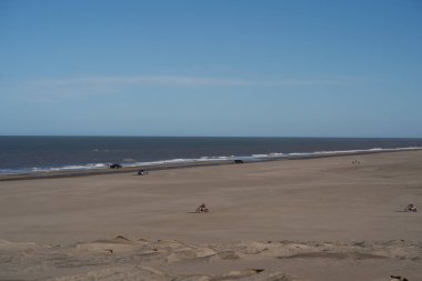 Güneşli bir günde kumsalın geniş bir görüntüsü. Açık bir gökyüzü ve görünürde kimse yok.