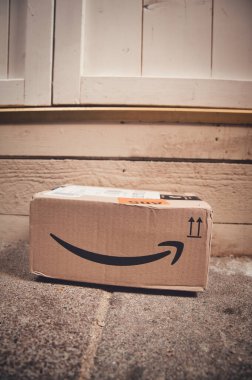 Tahta kapının önüne bırakılmış bir Amazon paket karton kutu.