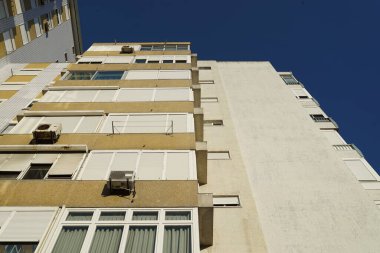 Açık mavi gökyüzüne karşı bir apartman kompleksinin alçak açılı görüntüsü