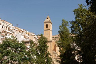 Alcala del Jucar şehrinin manzarası binalar ve bulutsuz bir gökyüzüne karşı bir tepenin üzerinde yer alan bir kule