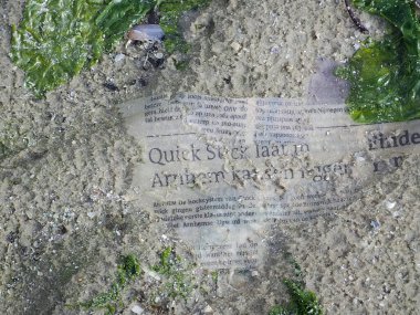 Hollanda, Ameland 'daki Wadden Denizi' nin kıyısındaki bir sahilde, yerdeki yazıtların en üst görüntüsü.