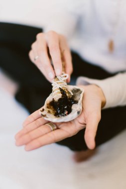 Adaçayı yakan ve deniz kabuğunun üzerinde tutan bir kadının dikey yakın çekimi..