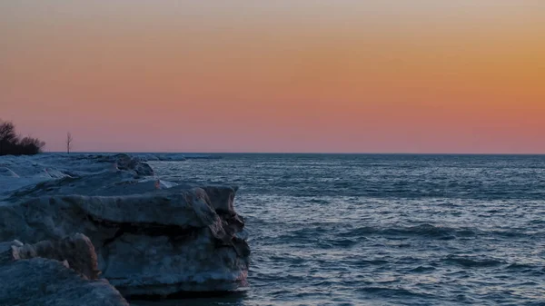 Eine Langzeitbelichtungsaufnahme Eines Meeres Bei Sonnenuntergang Mit Felsen Vordergrund — Stockfoto