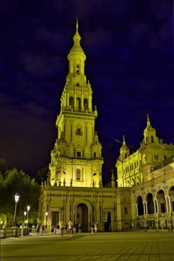 Sevilla meydanında karanlık bir gece gökyüzüne karşı bir kulenin dikey çekimi.