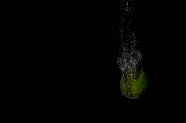 Siyah arka planda su sıçrayan bir limon.