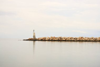 Sakin denizin yakınındaki kayalık bir sahilde bir deniz feneri, huzur ve huzur havası.
