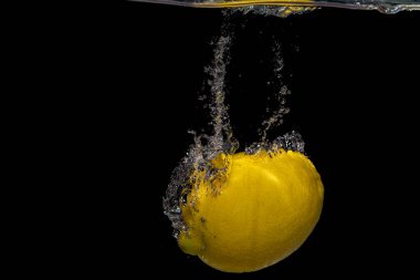 Suyun altındaki bir limonu yakından çek. Siyah bir arkaplanda izole edilmiş.