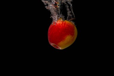 Siyah arkaplanda kırmızı bir elmanın yakın plan fotoğrafı.