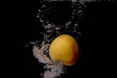 Siyah arka planda su sıçratan bir elma.