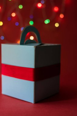 Kırmızı yüzey üzerinde izole edilmiş kırmızı yatay yay ile beyaz kutunun dikey görüntüsü..