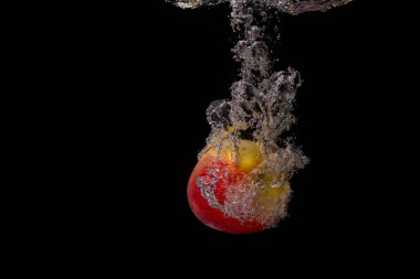 Stüdyoda çekilen temiz suda boğulan bir elma resmi ve siyah bir arkaplan.