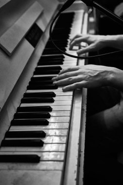 Piyano çalan ellerin dikey gri tonda çekimi