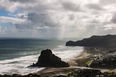 Bulutlu bir gökyüzünün altında, deniz kıyısındaki güzel bir uçurum manzarası.
