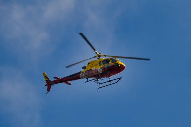 Fransa 'nın Cote d' Azur şehrinde mavi gökyüzüne uçan bir itfaiye helikopterinin alçak açılı çekimi.