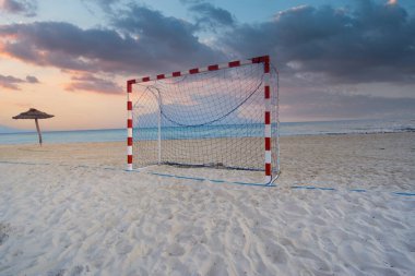 Güneşin batışında kumlu bir plajda, deniz kenarında güzel bir futbol kapısı görüntüsü.