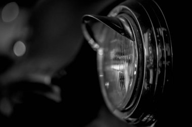 Eski model bir araba farının gri tonlu yakın çekimi.