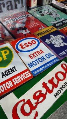 Bir sokak pazarında dikey motor yağı ve araba hatıra tabelaları.