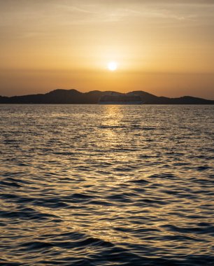 Hırvatistan 'da dağlarla çevrili bir denizde gün batımının güzel bir görüntüsü