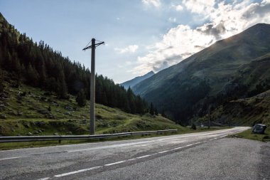 Dağlarda boş bir yol ve bir direği olan bir manzara.