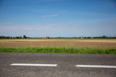 Mavi bulutsuz bir gökyüzünün altındaki açık kırsal bir arazinin çarpıcı manzarası, yol manzarası.