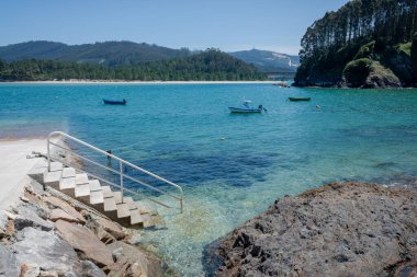 İspanya 'nın Barqueiro şehrinde deniz suyunda üç teknenin büyüleyici görüntüsü.