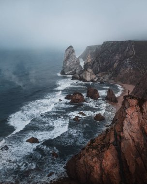 Portekiz 'de Atlantik Okyanusu' nda kayalarla dolu Ursa sahilinin dikey görüntüsü.