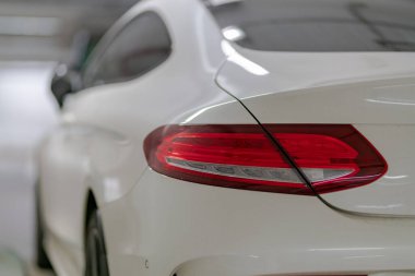 Bulanık arkaplanda beyaz bir arabanın yakın plan çekimi.