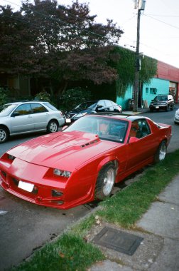 Şehir merkezindeki bir sokakta klasik kırmızı bir Chevrolet Camaro 'nun dikey görüntüsü.