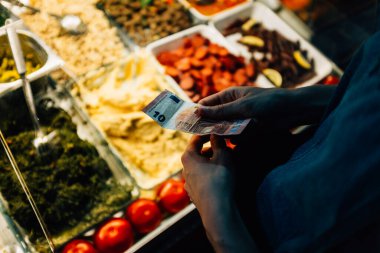 Gıda arka planında 10 avroluk banknot tutan kişilerin yakın çekimi.