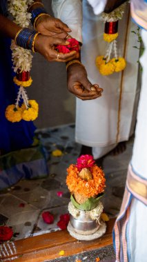 Dikey çekimde hindistancevizli bakır Kalash ve Hindu puja çiçekli mango yaprağı.