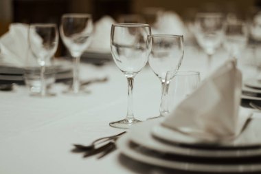 Nazikçe katlanmış bir peçetenin ve yemek masasının üzerinde duran bardakların yakın plan fotoğrafı.