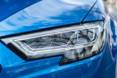 Mavi bir arabanın farının yakın çekimi.