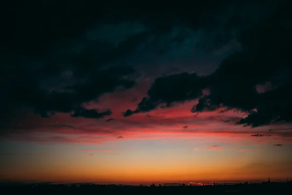 赤い地平線と暗い雲とカラフルな夕日の空の魅惑的なシーン — ストック写真