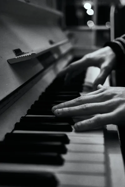 ピアノを演奏する手の垂直グレースケールショット — ストック写真