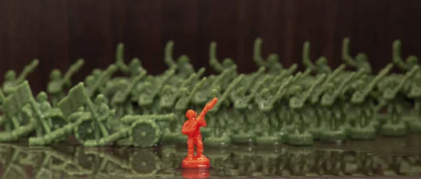 一个红色小兵的缩影和其他绿色士兵模糊的背景 — 图库照片
