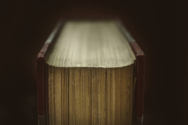 A soft focus of the corner of pages of a hardbound book against a black background