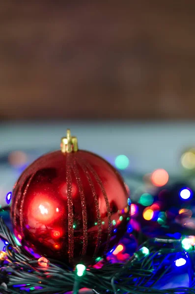 背景がぼやけてカラフルなライトの文字列に赤いクリスマスボールのクローズアップショット — ストック写真