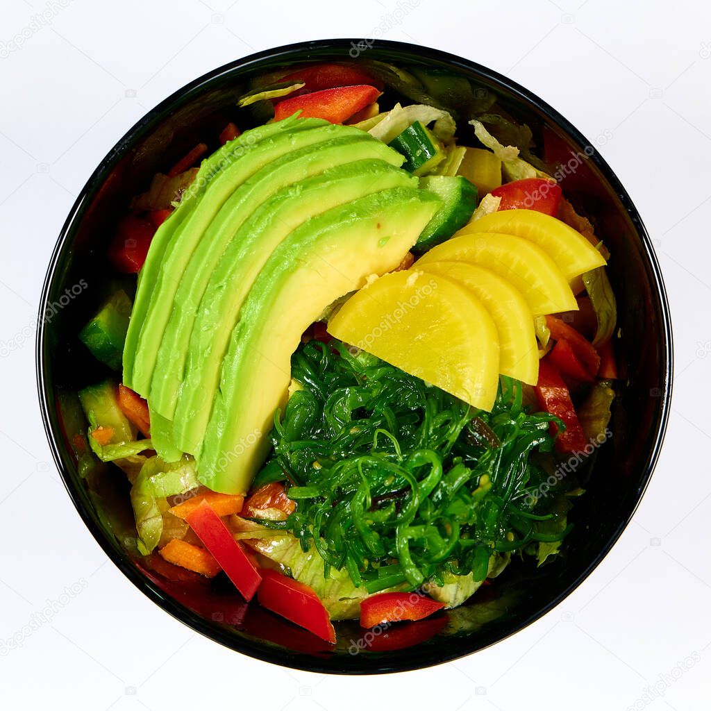 A top view of the vegetable salad with sliced avocados isolated on the white background
