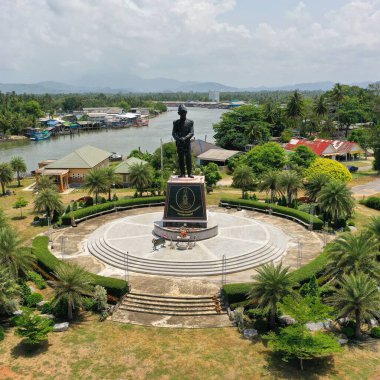Ortasında erkek heykeli, arkasında nehir olan küçük bir kare.