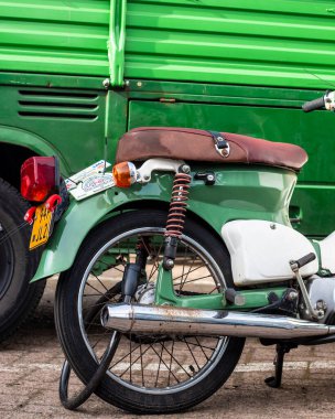 Yeşil bir otobüsün önündeki yeşil bir motosikletin dikey çekimi.