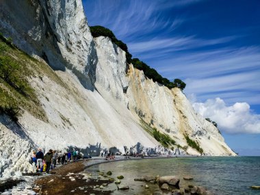 Mavi güneşli bir gökyüzüne karşı yüksek kayalık dağların altında yürüyen insanların güzel bir manzarası.